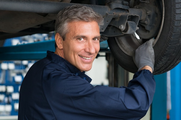 Portrait Of Happy Mature Mechanic At Repair Service Station