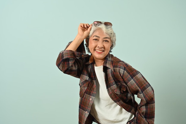 Portrait of happy mature woman wearing plaid shirt posing isolated on bright blue color background