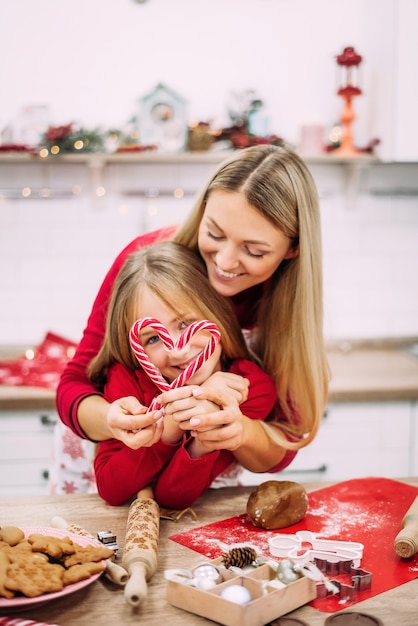 Portrait of happy mom and daughter standing in the kitchen and preparing gingerbread cookies