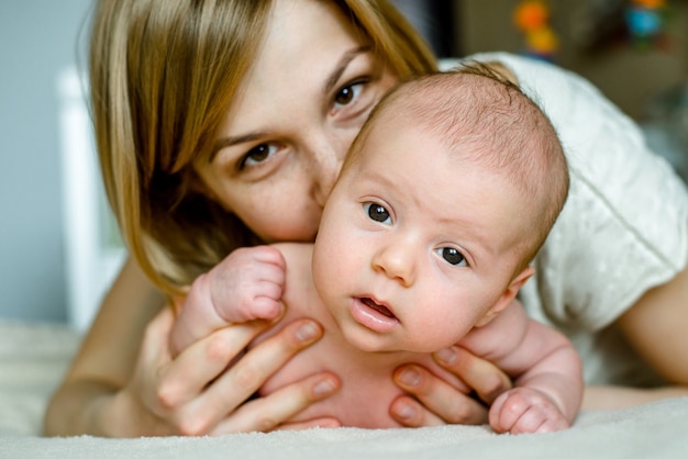 Portrait of happy mother and baby at home. The child is 2 months