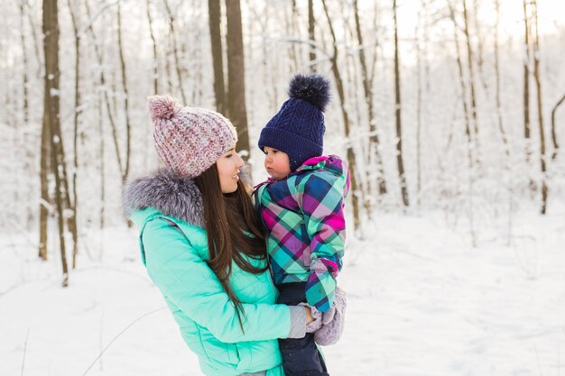 Portrait of happy mother and baby in winter park.