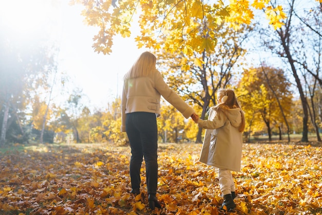 Portrait of happy mother and daughter in autumn forest at sunset Autumn women