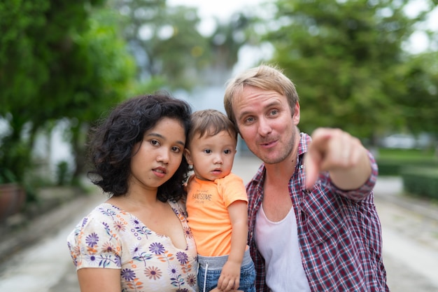 Portrait of happy multi-ethnic family with one child bonding together outdoors