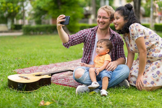 Portrait of happy multi-ethnic family with one child bonding together outdoors