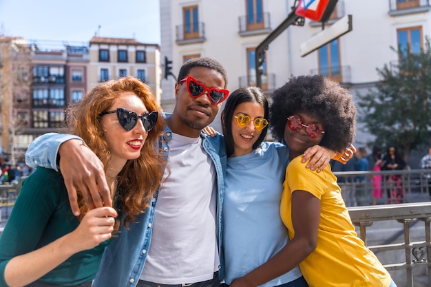 Portrait of happy multiethnic friends wearing sunglasses on the city street laughing together outdoors