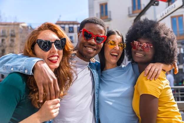 Portrait of happy multiethnic friends wearing sunglasses on the city street laughing together outdoors