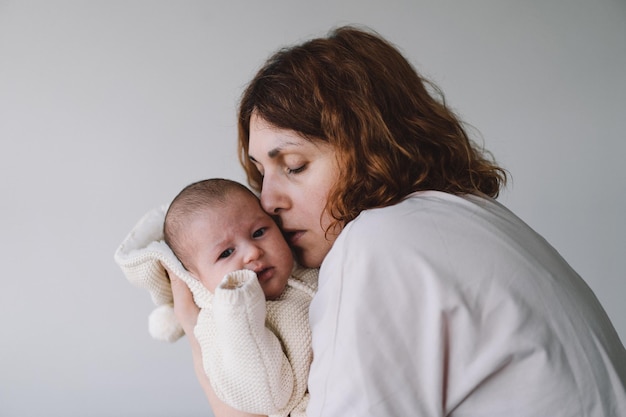 Portrait of happy mum holding infant child on hands Loving mom carying of her newborn baby at home Mother hugging her little 1 months old girl