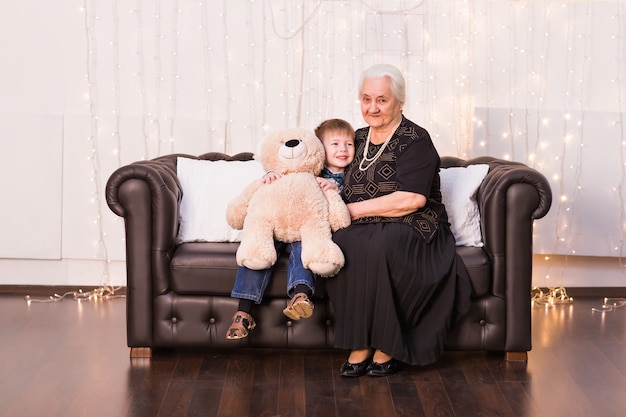 Portrait of happy old granny and her grandson hugging, looking at camera and smiling