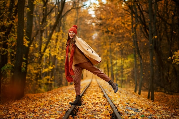 Portrait of happy overjoyed woman in jump over railroad in autumn forest. Excitement and fall weather