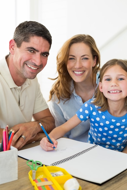 Portrait of happy parents assisting girl in drawing at home 