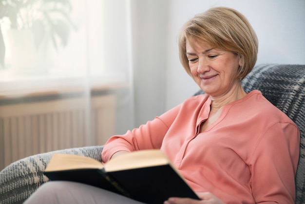 Portrait of happy positive beautiful intelligent adult senior woman is reading interesting funny