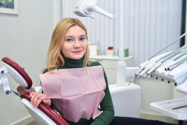 Portrait of happy positive cheerful blonde European girl young satisfied smiling woman patient with perfect smile is lying having a seat in medical chair in dental office after treatment in clinic