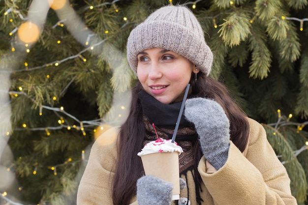 Portrait of a happy pretty girl with a drink during Christmas holidays in  at a Christmas fair