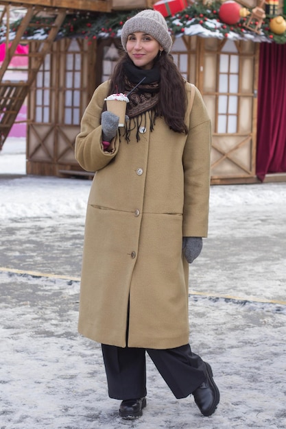 Portrait of a happy pretty girl with a drink during Christmas holidays in a festive town