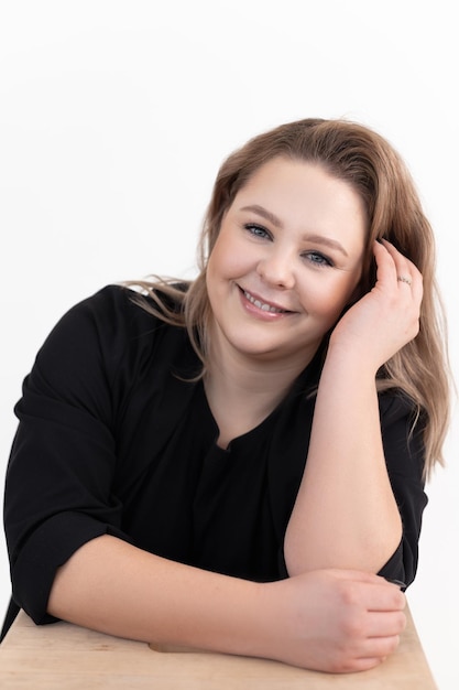 Portrait of happy pretty middleaged fat woman with long dark hair and makeup wearing black cardigan