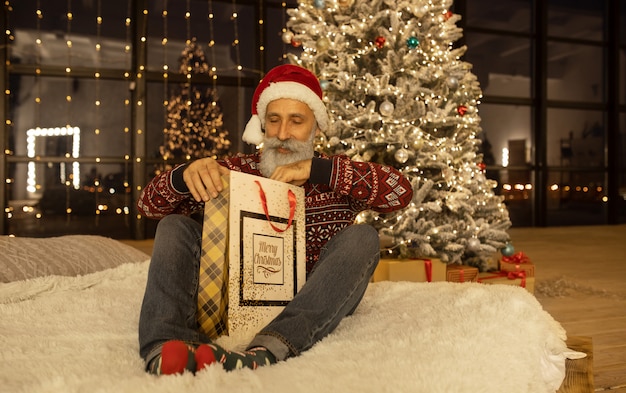 Portrait of happy Santa Claus at his room at home near Christmas tree.