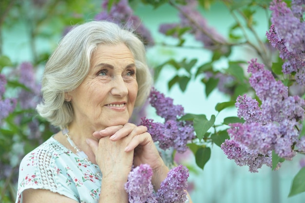 Portrait of happy senior beautiful woman on lilacs background