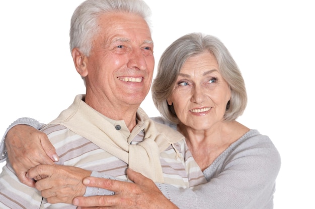 Portrait of happy senior couple hugging on white background