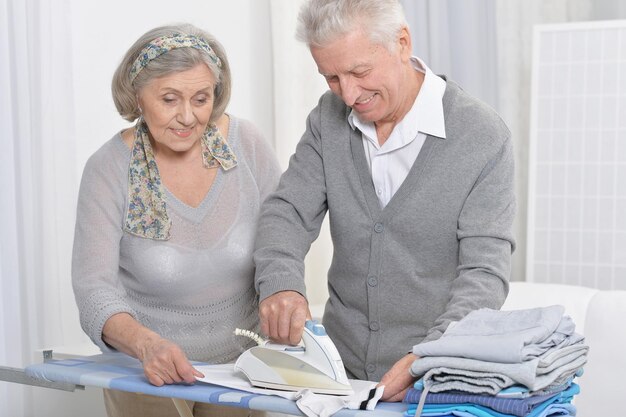 Portrait of happy senior couple during ironing