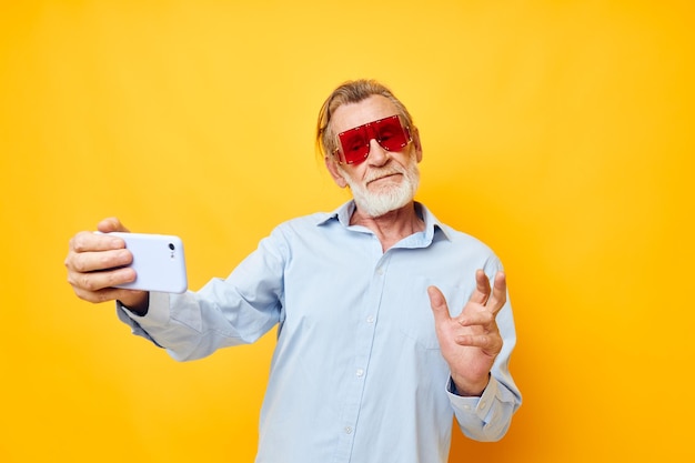 Portrait of happy senior man blue shirts with glasses takes a selfie unaltered