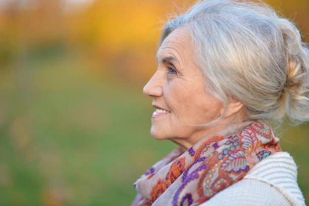 Portrait of happy senior woman in autumn park