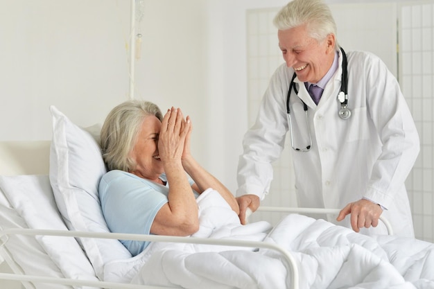 Portrait of happy senior woman in hospital with caring doctor