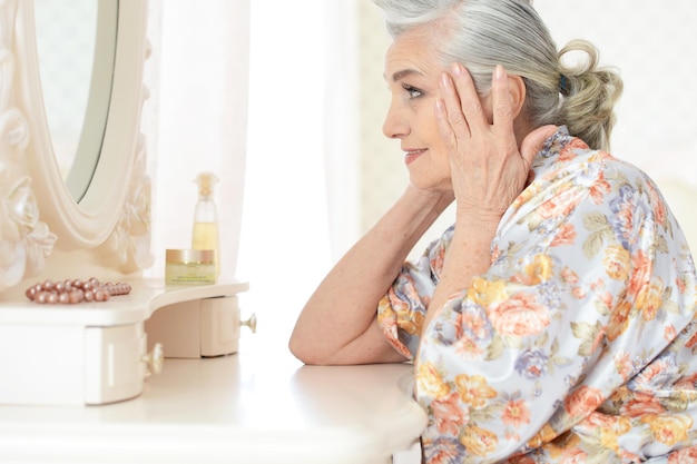 Portrait of happy senior woman sitting near dressing table