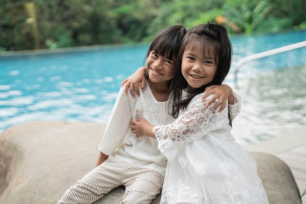 Portrait of happy sisters pictured in a swimming pool background