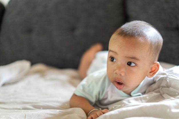 Portrait of happy smile asian baby boy relaxing looking at cameraCute asian newborn child on the bed at home