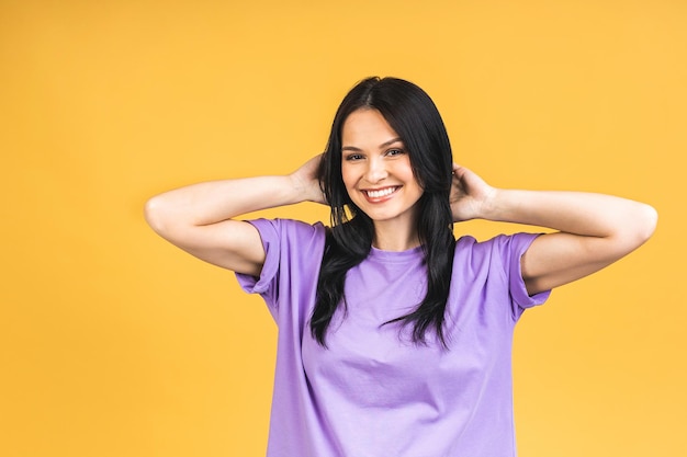 Portrait of happy smiling brunette girl in casual isolated over yellow background