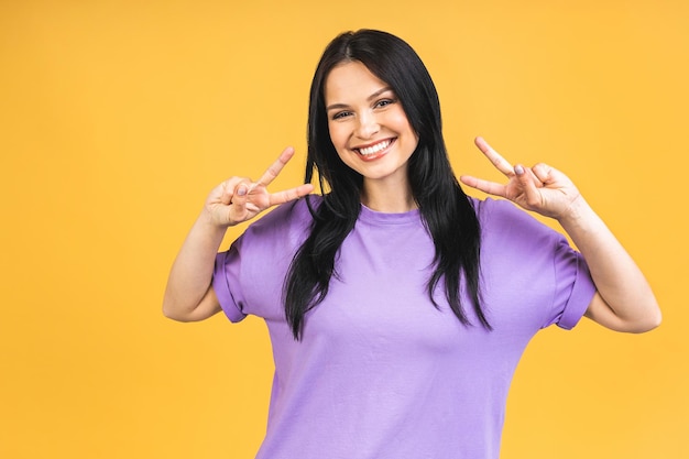 Portrait of happy smiling brunette girl in casual isolated over yellow background