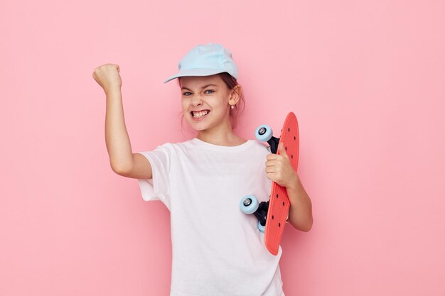 Portrait of happy smiling child girl cap in white tshirt skateboard isolated background