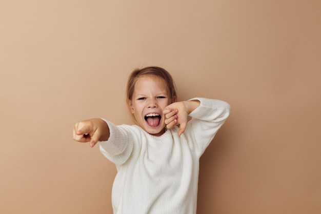 Portrait of happy smiling child girl joy posing emotions fashion beige background