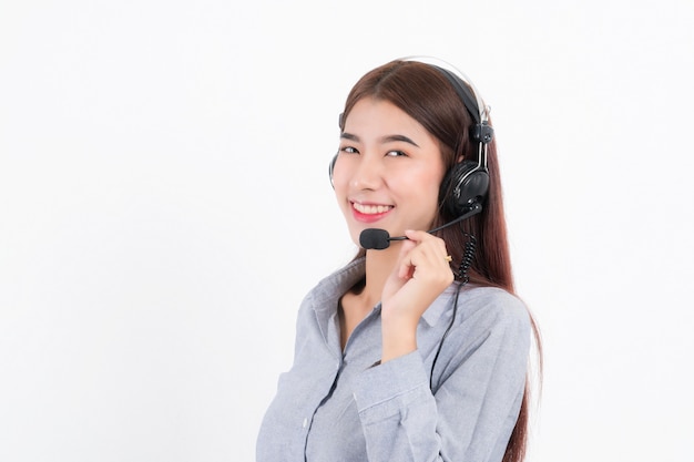 Portrait of happy smiling female customer support phone operator short hair, wearing a gray shirt with headset standing one side holding the earphone isolated on white background.