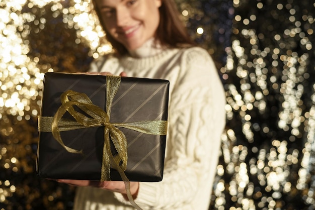 Portrait of a happy smiling girl holding a golden gift box on a golden background