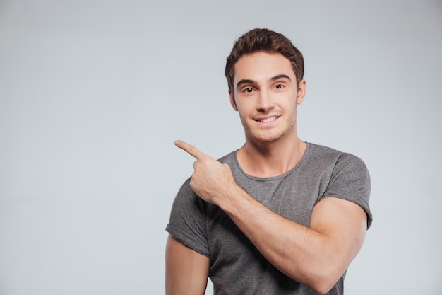 Portrait of a happy smiling man pointing finger away at copyspace isolated on white