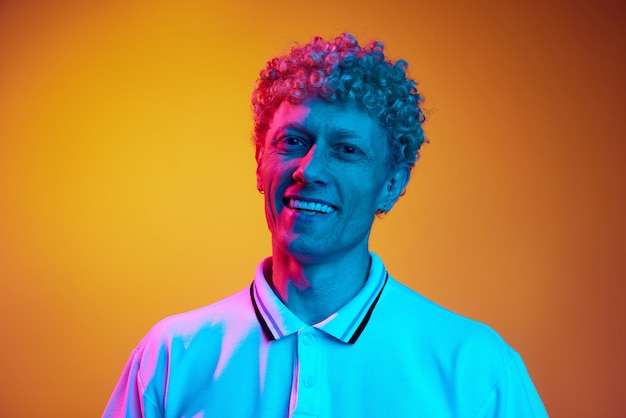 Portrait of happy smiling mature man with curly hair looking at camera posing against orange studio