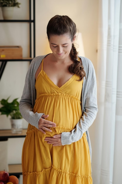 Portrait of happy smiling pregnant young woman touching her belly