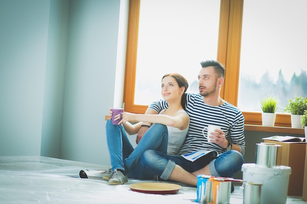 Portrait happy smiling young couple painting interior wall of new house Young couple