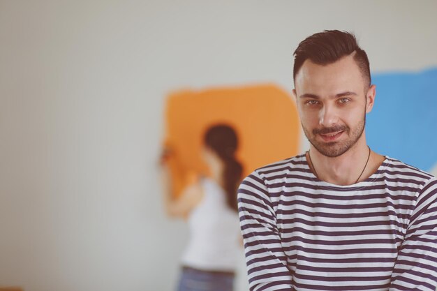 Portrait of happy smiling young couple painting interior wall of new house young couple