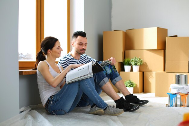 Portrait happy smiling young couple painting interior wall of new house Young couple