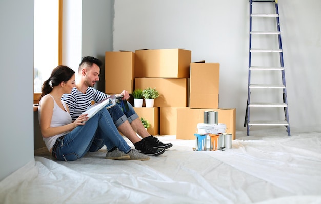 Portrait happy smiling young couple painting interior wall of new house Young couple