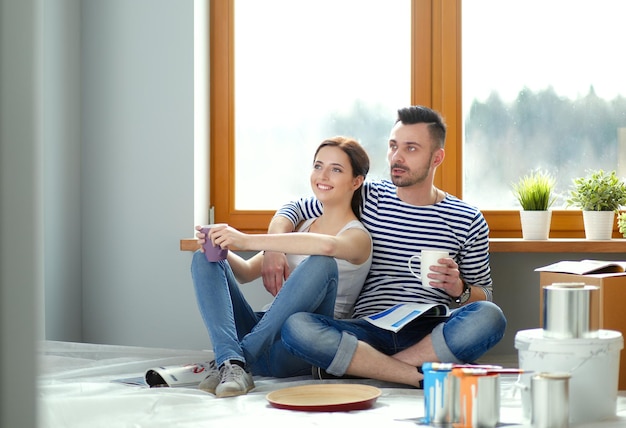 Portrait happy smiling young couple painting interior wall of new house Young couple