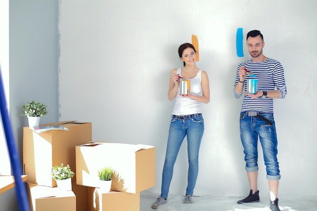 Portrait of happy smiling young couple painting interior wall of new house young couple