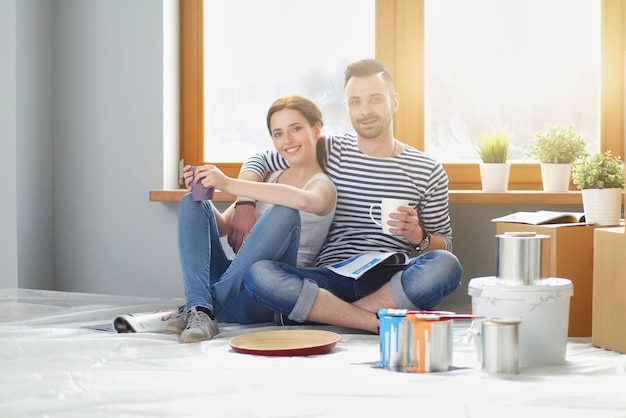 Portrait happy smiling young couple painting interior wall of new house. Young couple