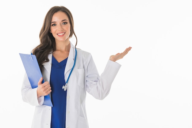 Portrait of happy smiling young female doctor showing something or blank area for text, or copyspace, isolated over white surface