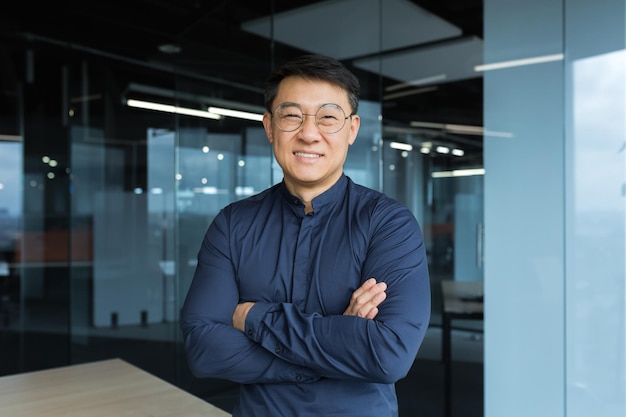 Portrait of happy and successful asian businessman man in glasses smiling and looking at camera