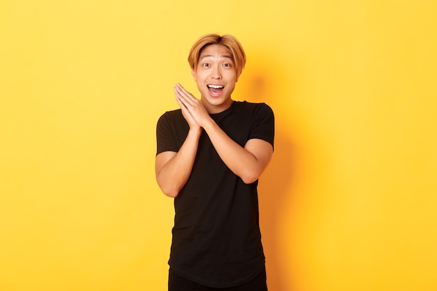 Portrait of happy and surprised asian man clap hands and smiling delighted