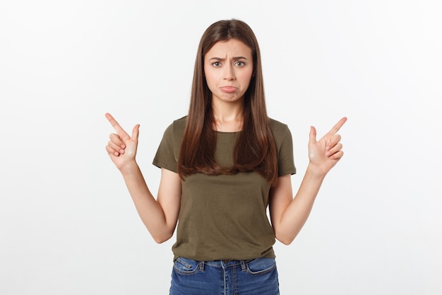 Portrait happy and surprised young lady standing isolated over grey background. Looking camera pointing.