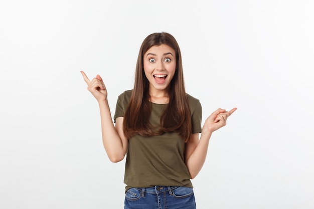 Portrait happy and surprised young lady standing isolated over grey background. Looking camera pointing.